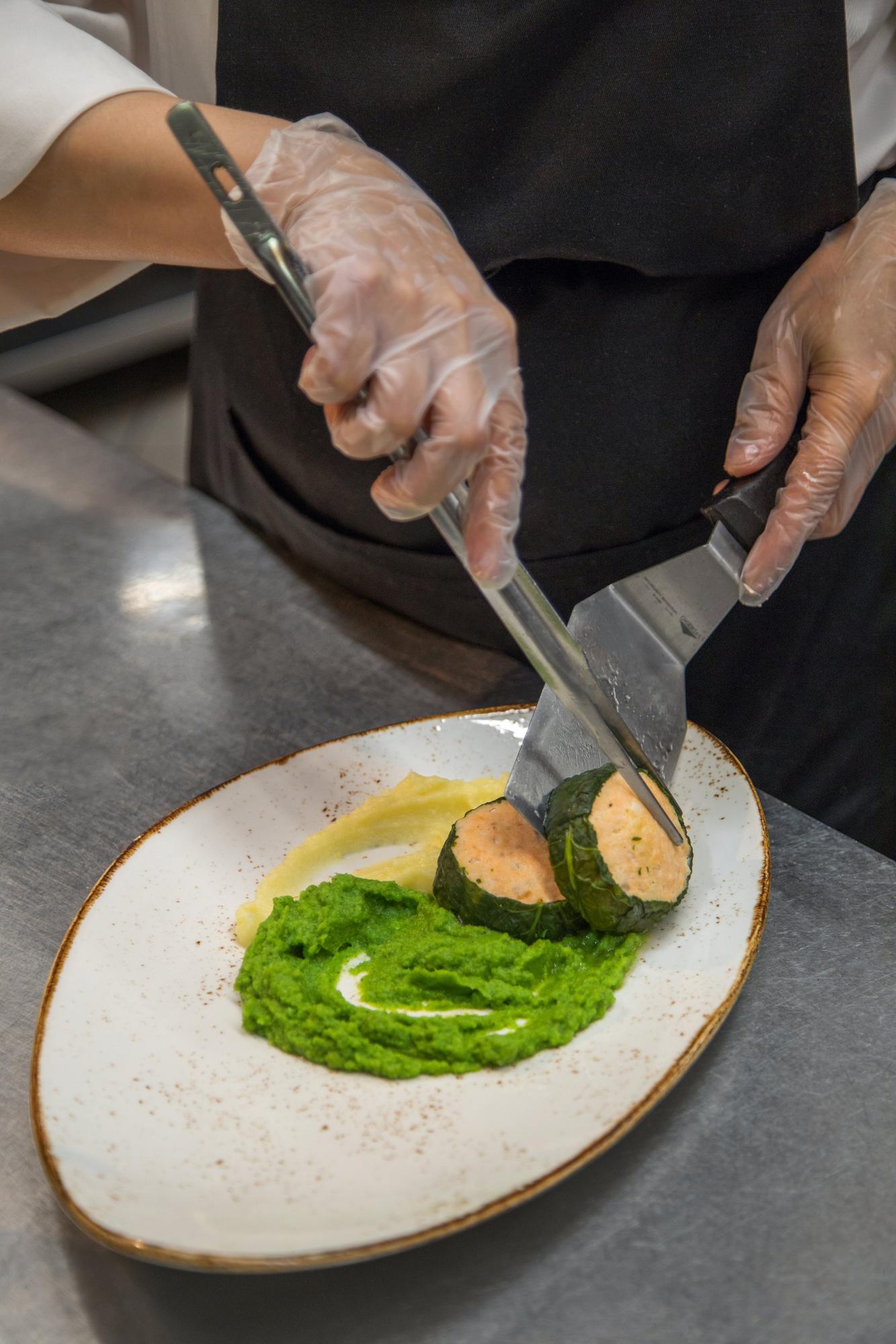 Chef arranging a plated dish with herbs